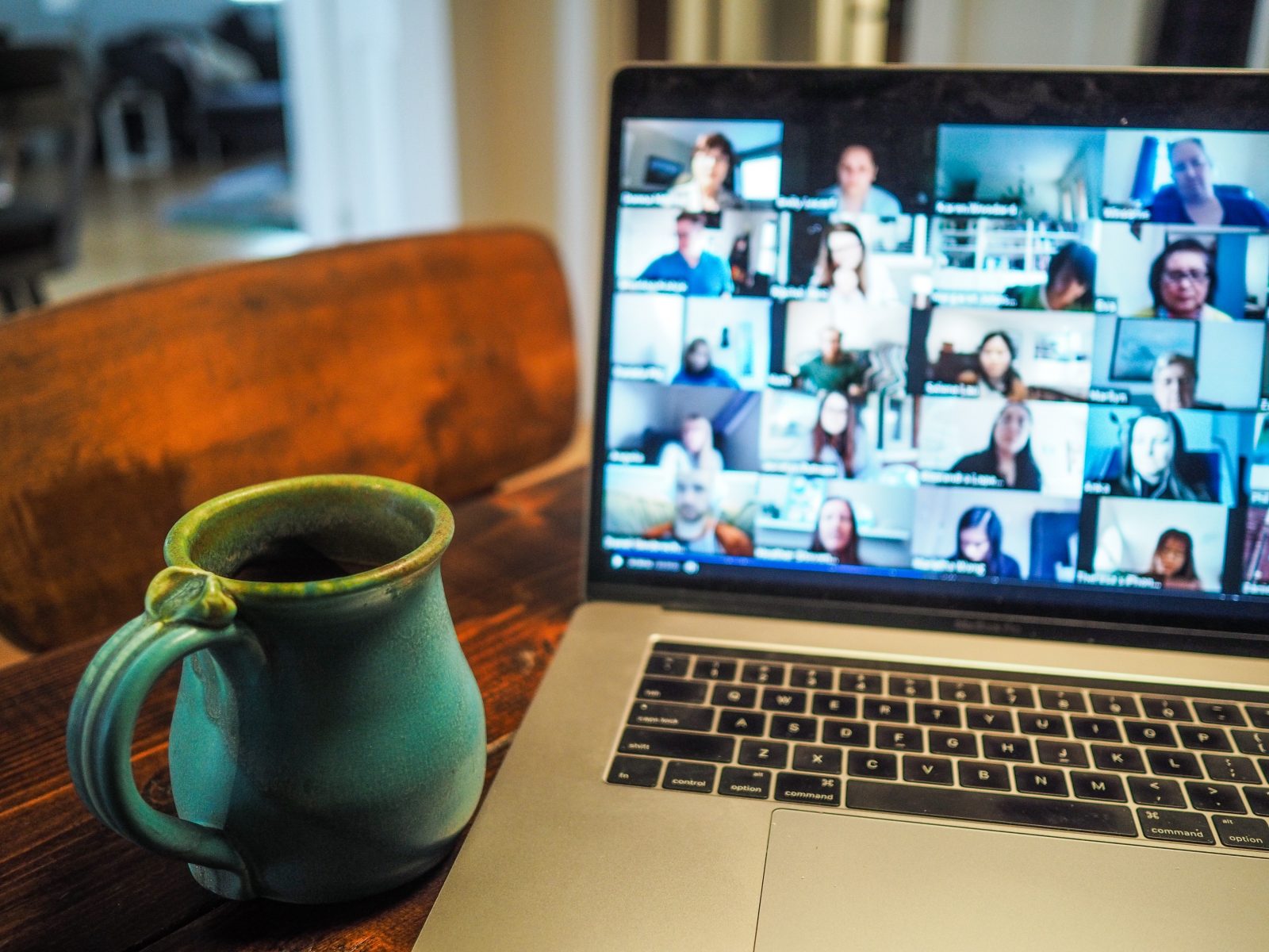 En kaffekop er stillet ved siden af en computer med en videomøde på skærmen. 
