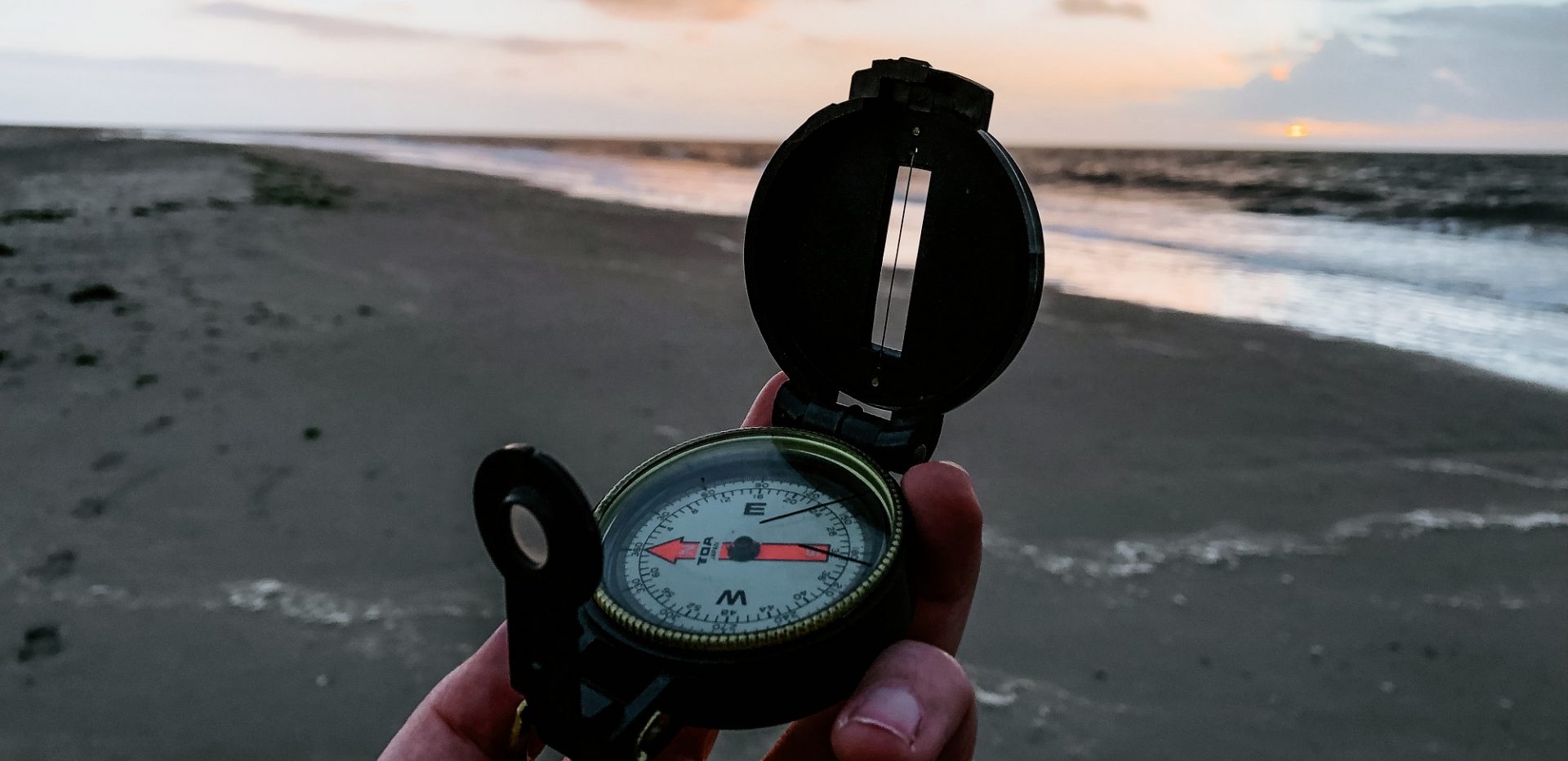 Kompas holdes i hånden på en strand