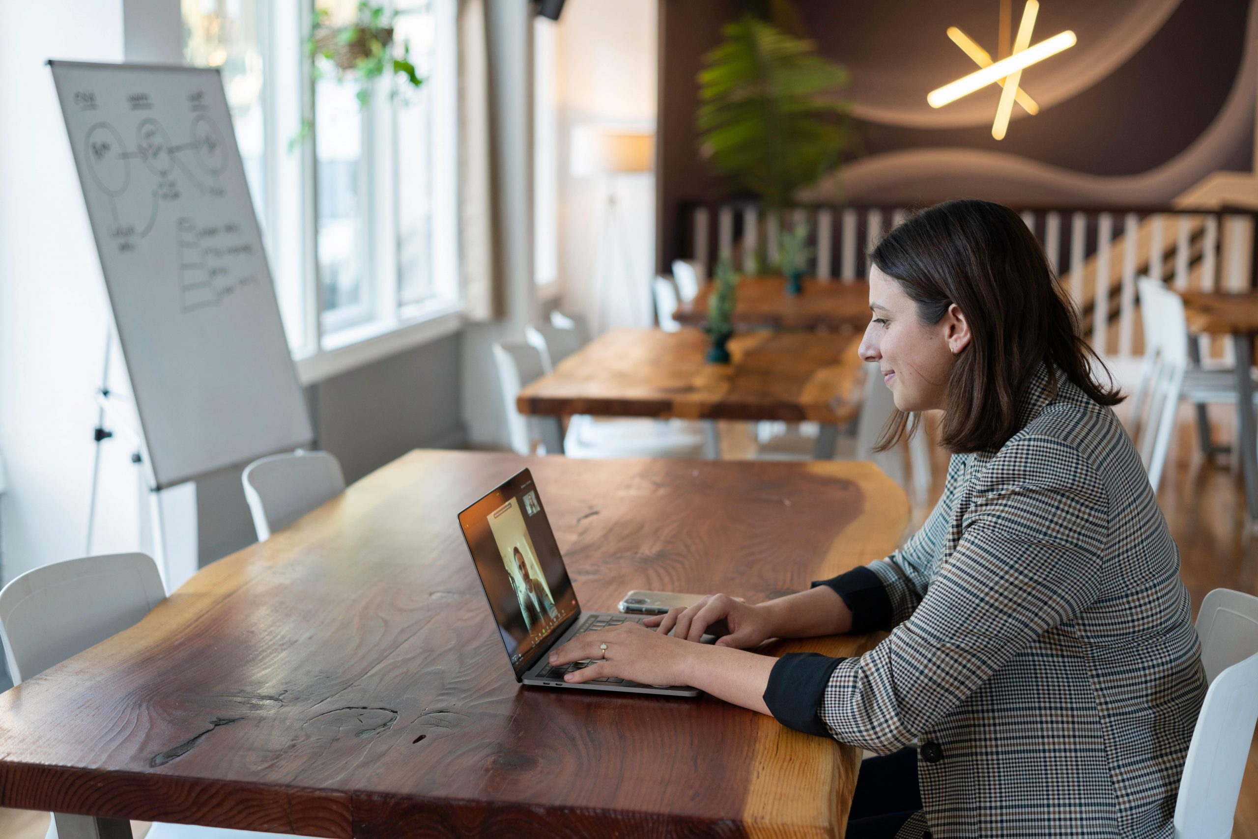 Kvinde sidder ved skrivebord og deltager i online møde på computer.
